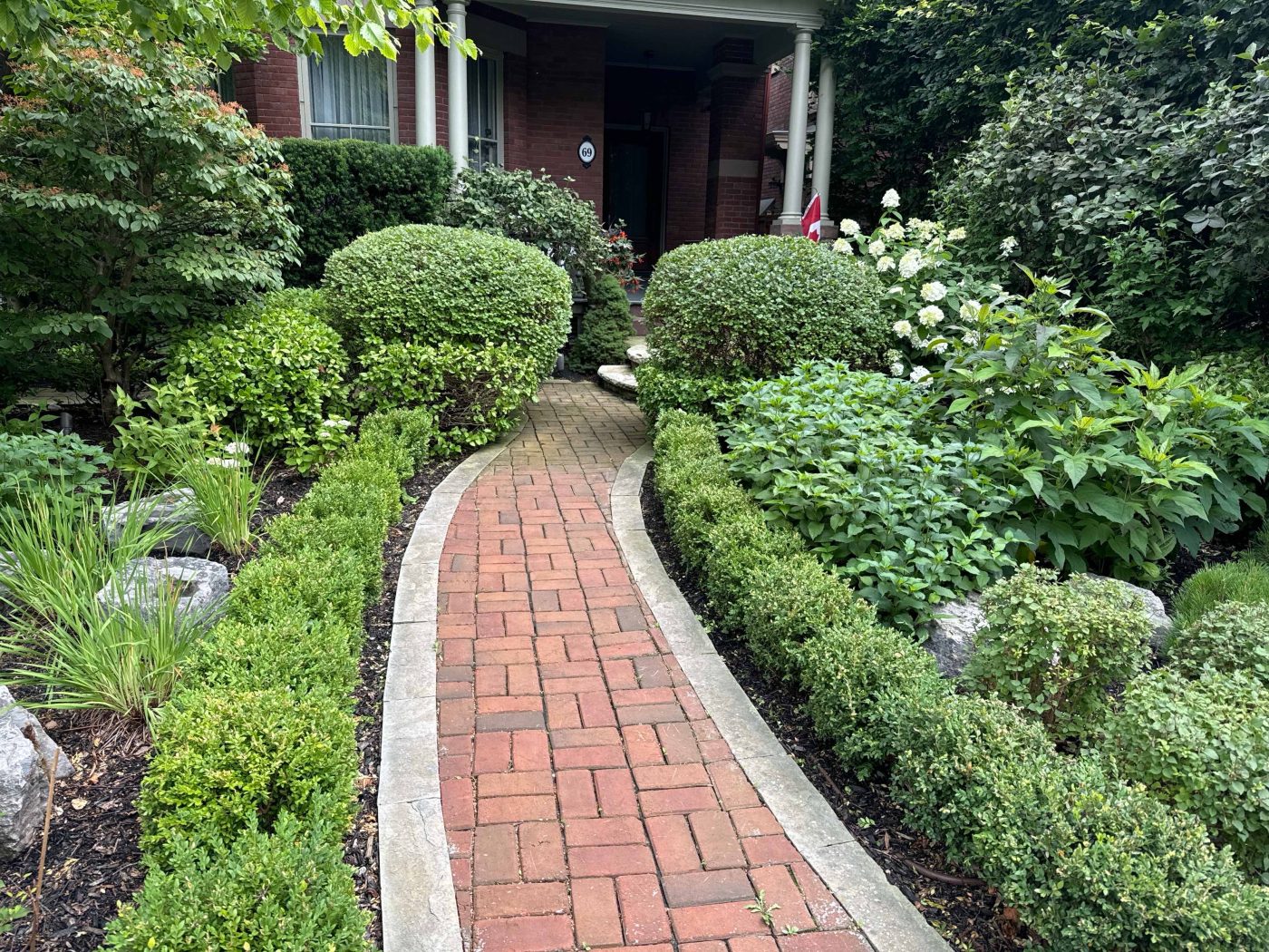 Brick Interlock pathway with Boxwoods on either side to hold in gardens